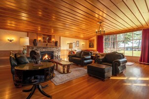 Un salón amplio con muebles de cuero, chimenea y ventanas grandes.
