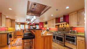 A modern kitchen with wooden cabinets, stainless steel appliances, and a central island with bar stools. - Historic  Gilchrist Waterfront Resort (Crescent)
