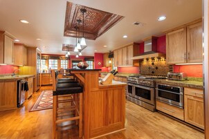 Una cocina moderna con gabinetes de madera, electrodomésticos de acero inoxidable y una isla central con taburetes de bar.