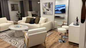 Una sala de estar moderna con un sofá, dos sillones, una mesita de centro y un televisor.