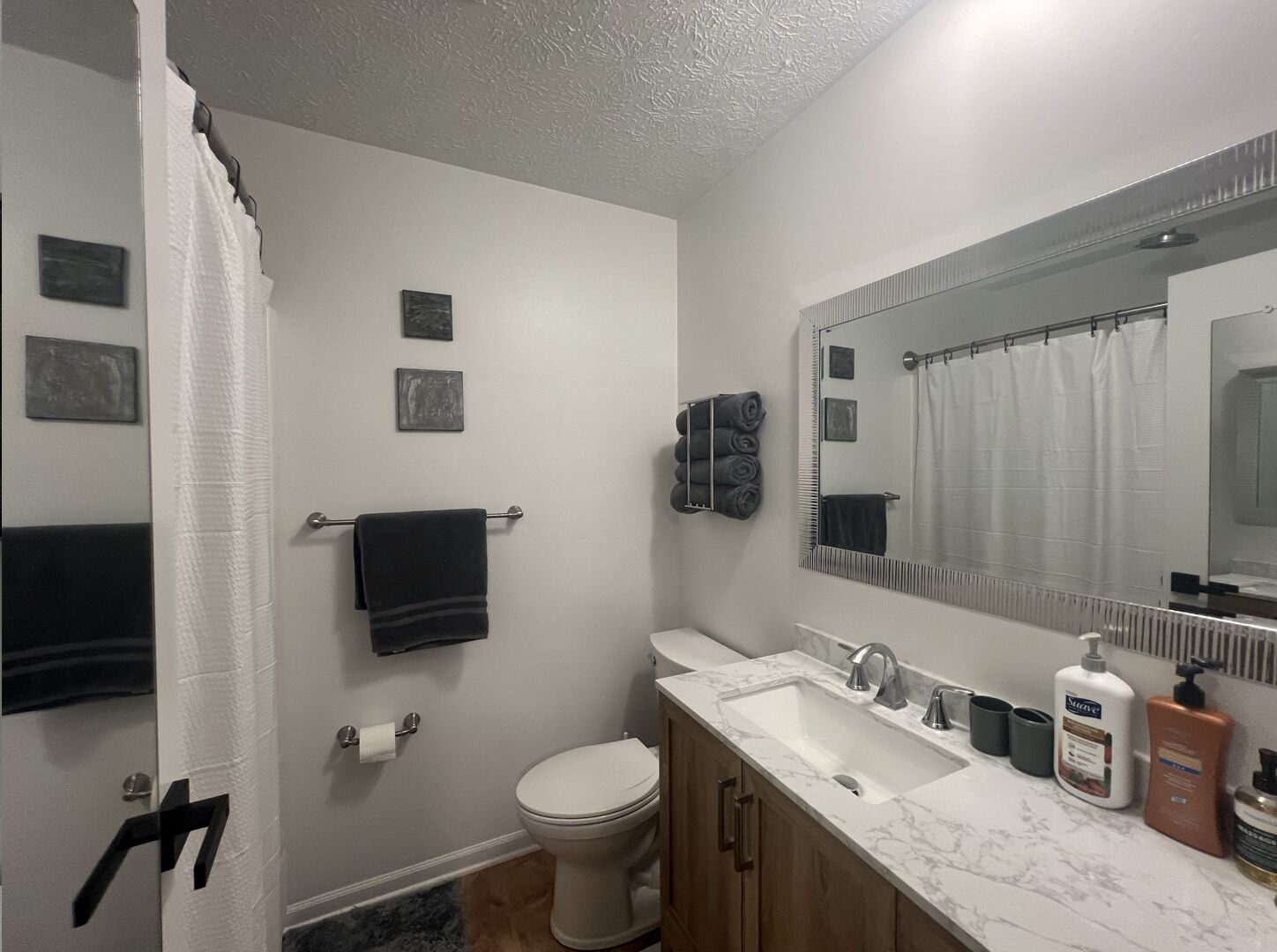 Un baño con inodoro, lavabo y espejo. Hay toallas y artículos de aseo en la encimera.