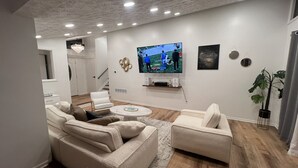 Una sala de estar moderna con un televisor de pantalla plana montado en la pared, un sofá, una mesa de centro y una planta en maceta.