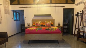 A bedroom with a wooden bed, a nightstand, a chair, and a wardrobe. - Manta-Ray Beach Unit 2 (Rarotonga)