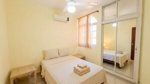 Un dormitorio con cama, mesita de noche y ventilador de techo.