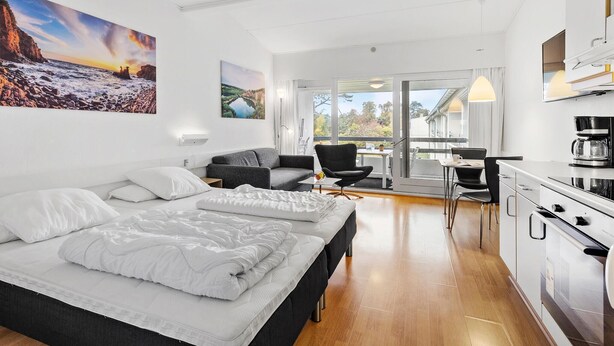 A modern hotel room with a large bed, a sofa, a dining area, and a kitchen. - Amazing apartment in Nexø with WiFi (Nexø)
