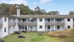 A two-story building with a covered patio area, outdoor seating, and a grassy lawn. - Amazing apartment in Nexø with WiFi (Nexø)