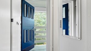 A hallway with a blue door and a white door leading to a balcony. - Amazing apartment in Nexø with WiFi (Nexø)