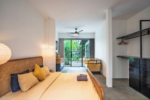 A hotel room with a bed, bedside lamps, a ceiling fan, and a view of the outdoors.