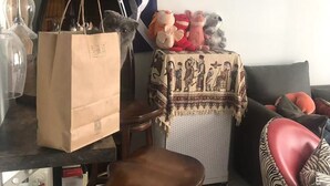 Un salon chaleureux avec une table basse en bois, un plaid à motifs sur un canapé, une lampe et une étagère ornée d’objets décoratifs.