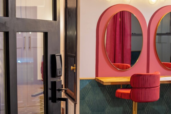 A room with a black door, a red chair, and a table with a mirror above it.