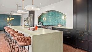 A modern kitchen with a large island, bar stools, and dark cabinetry. - Most EPIC Austin Experience! Sleeps 14 + heated Pool + Spa + Cabanas + Speakeasy (Austin)