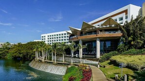 A modern hotel with a unique architectural design, featuring a large water feature and lush greenery. - Grand Luxxe 2 Bedroom Loft Residences 5 Diamonds all Platinum Access  (Nuevo Vallarta)