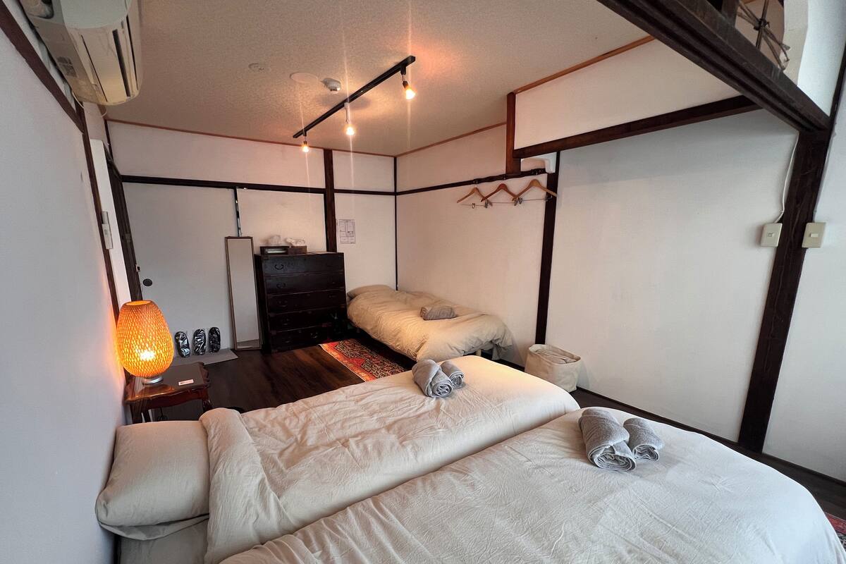 Habitación de hotel con dos camas, un aparador, un espejo y una lámpara colgante.