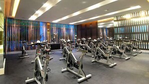 Ett gym med motionscyklar uppställda i rader, en modern takdesign och en färgglad vägg med vertikala linjer.