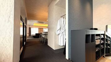Un corredor de hotel moderno con una zona de estar, una bata colgada y un mueble para guardar zapatos.