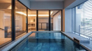 A modern interior with a glass-enclosed pool area, a visible bathroom with a bathtub, and a large window with blinds. - DOG HOTEL SHIRAHAMA (Shirahama)