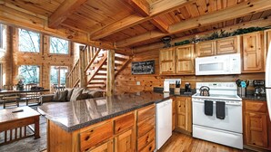 L’intérieur d’un chalet en bois comprend une cuisine, un coin repas et un escalier.