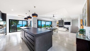 A modern kitchen with a central island, large windows, and a view of the outdoors.
