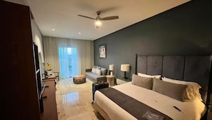 A hotel room with a large bed, a ceiling fan, a sofa, and a view of the outdoors.