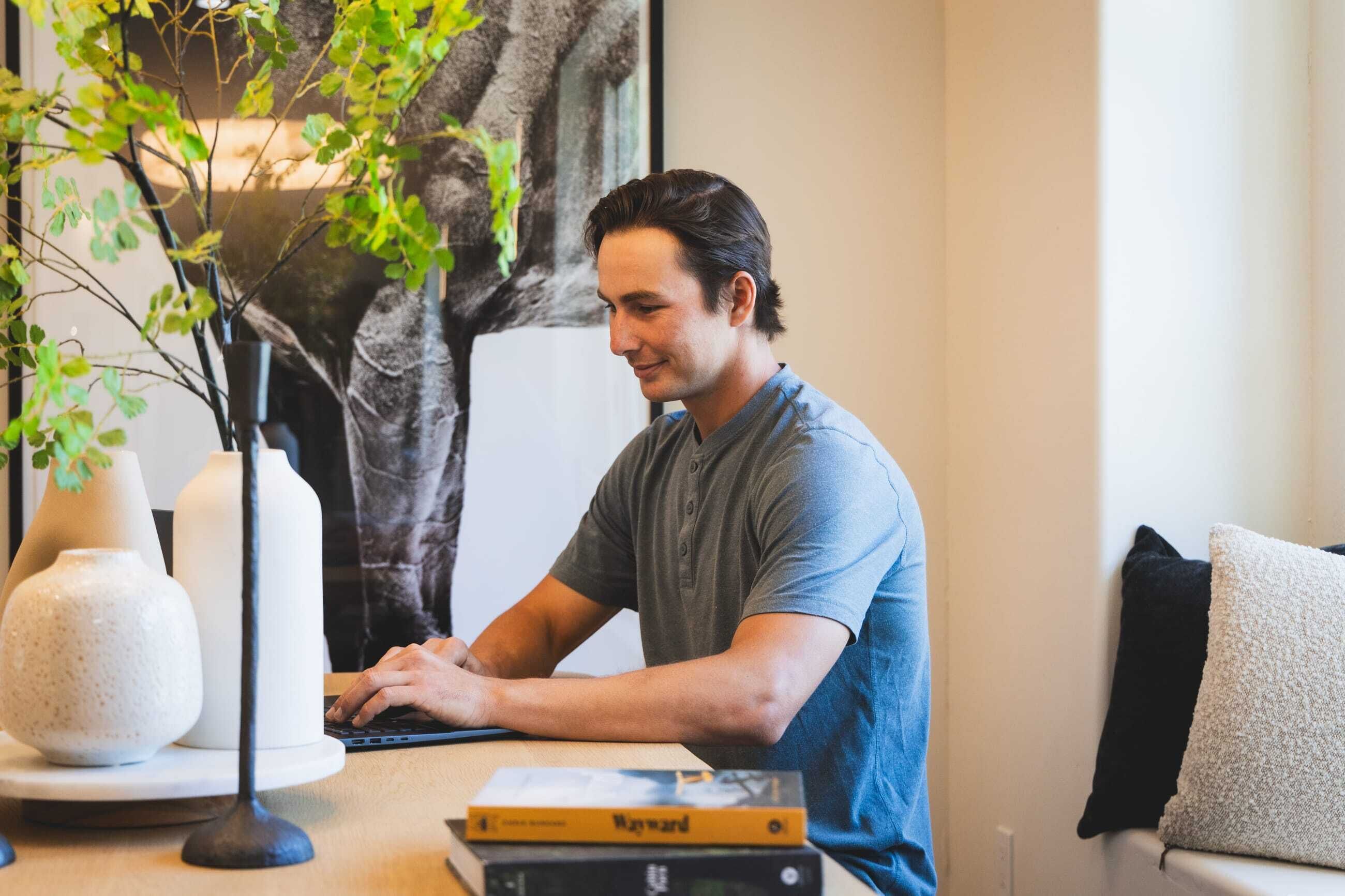 A person sitting at a desk with a laptop, a book, and decorative vases.