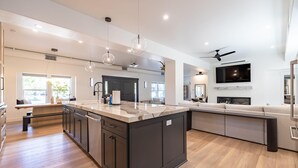 Une cuisine moderne dotée d’un grand îlot central, d’appareils électroménagers intégrés et d’un téléviseur à écran plat.