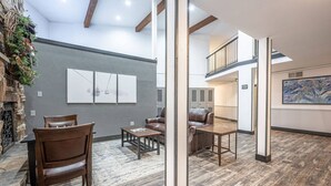 Eine großzügige Lobby mit Holzboden, Ledersitzmöbeln, einem Kamin und Blick auf Schließfächer sowie eine Treppe.