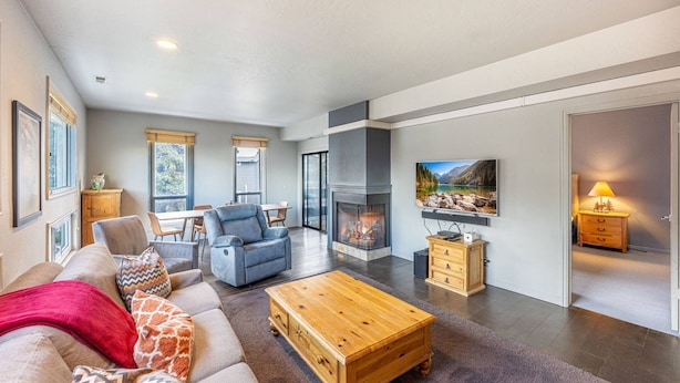 A modern living room with a fireplace, a sofa, a coffee table, and a TV mounted on the wall.