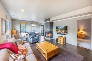 Una sala de estar moderna con chimenea, un sofá, una mesa de centro y un televisor montado en la pared.