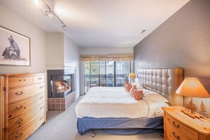 Un dormitorio con una cama grande, un aparador de madera, una chimenea y vistas al exterior.