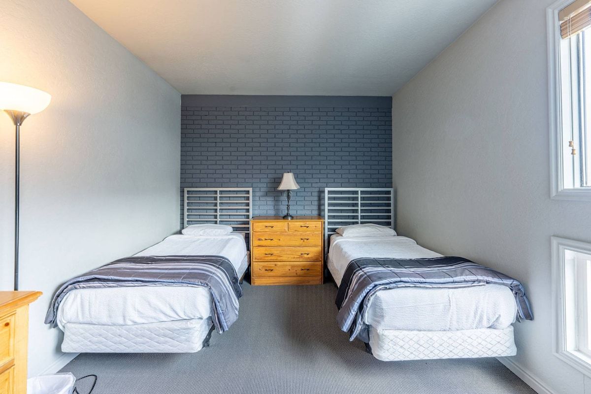 Ein Schlafzimmer mit zwei Betten, einem Schminktisch, einer Lampe und einer Wand mit Ziegeloptik.