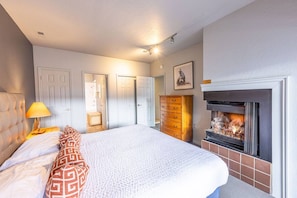 Ein Schlafzimmer mit Bett, Kommode, Kamin und einer Tür.