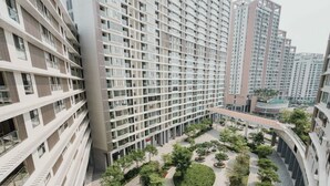 A modern high-rise residential building with multiple balconies, a central courtyard with trees and a circular water feature, and a view of adjacent buildings. - Midtown Citypoint Central Suites By An Gia Hospitality (Ho Chi Minh City)