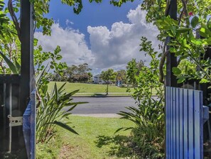 A gated entrance with a clear view of a road and a grassy area beyond. - Nestled on Nautilus (Kingscliff)