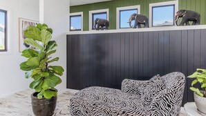 A modern living room with a zebra-patterned sofa, a large potted plant, and decorative elephant sculptures on a shelf. - Nestled on Nautilus (Kingscliff)