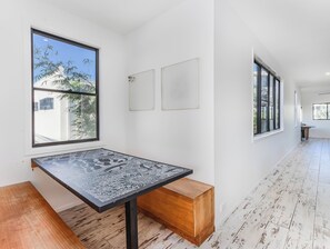 A room with a large window, a patterned table, and a wooden bench. - Nestled on Nautilus (Kingscliff)