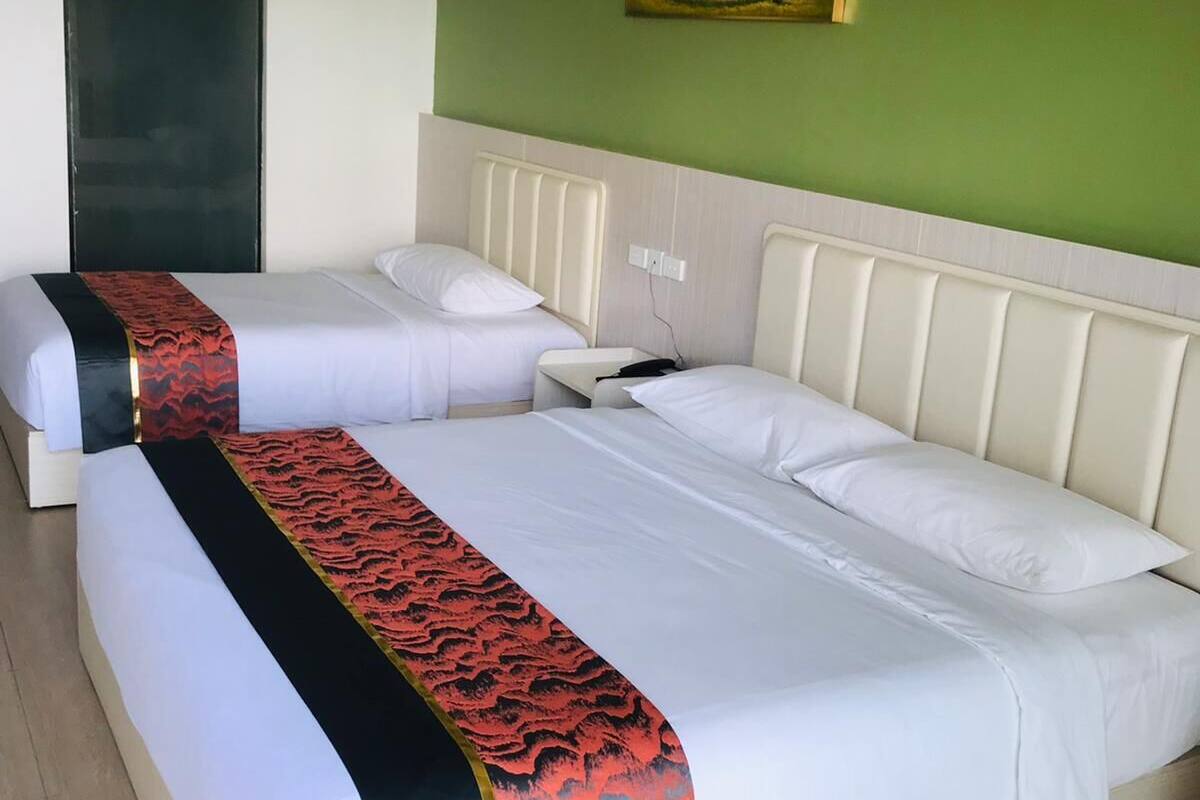 A hotel room with two beds, a painting on the wall, and a wooden floor.