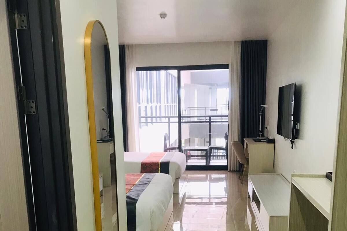 A hotel room with a bed, a desk, a TV, and a view of the outside.