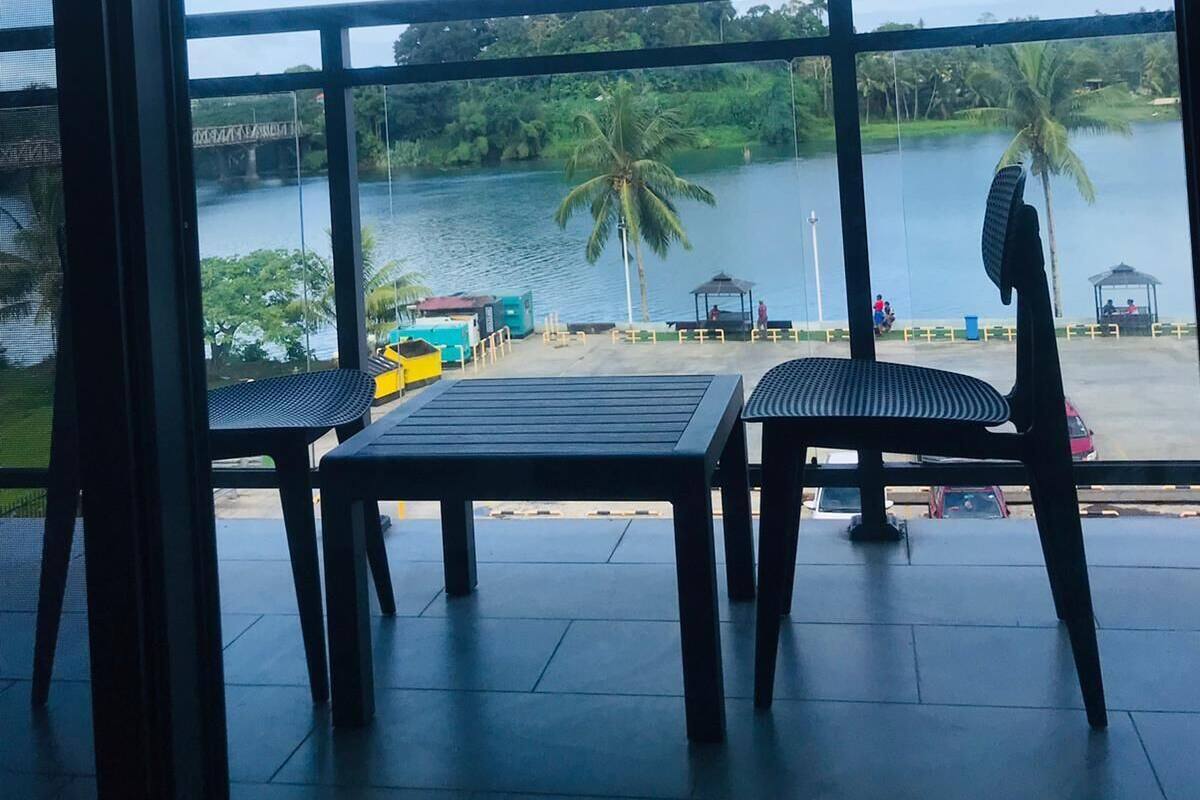 A balcony with a view of a lake, a bridge, and palm trees.
