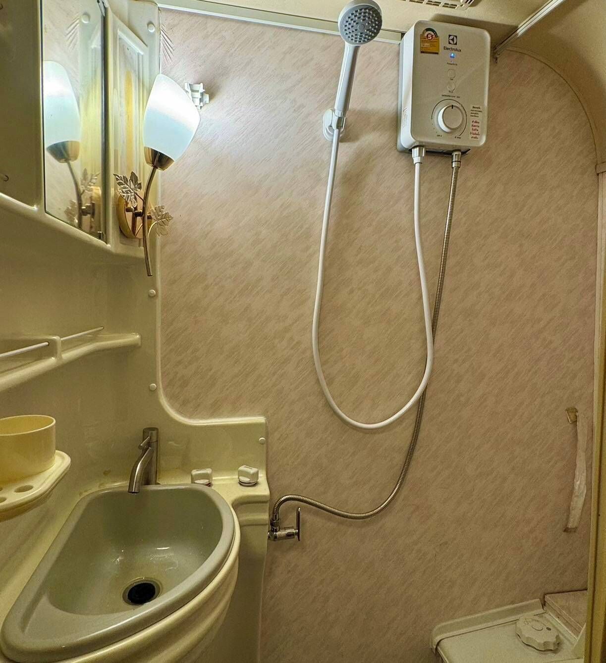 A compact bathroom with a shower, a sink, and a toilet.