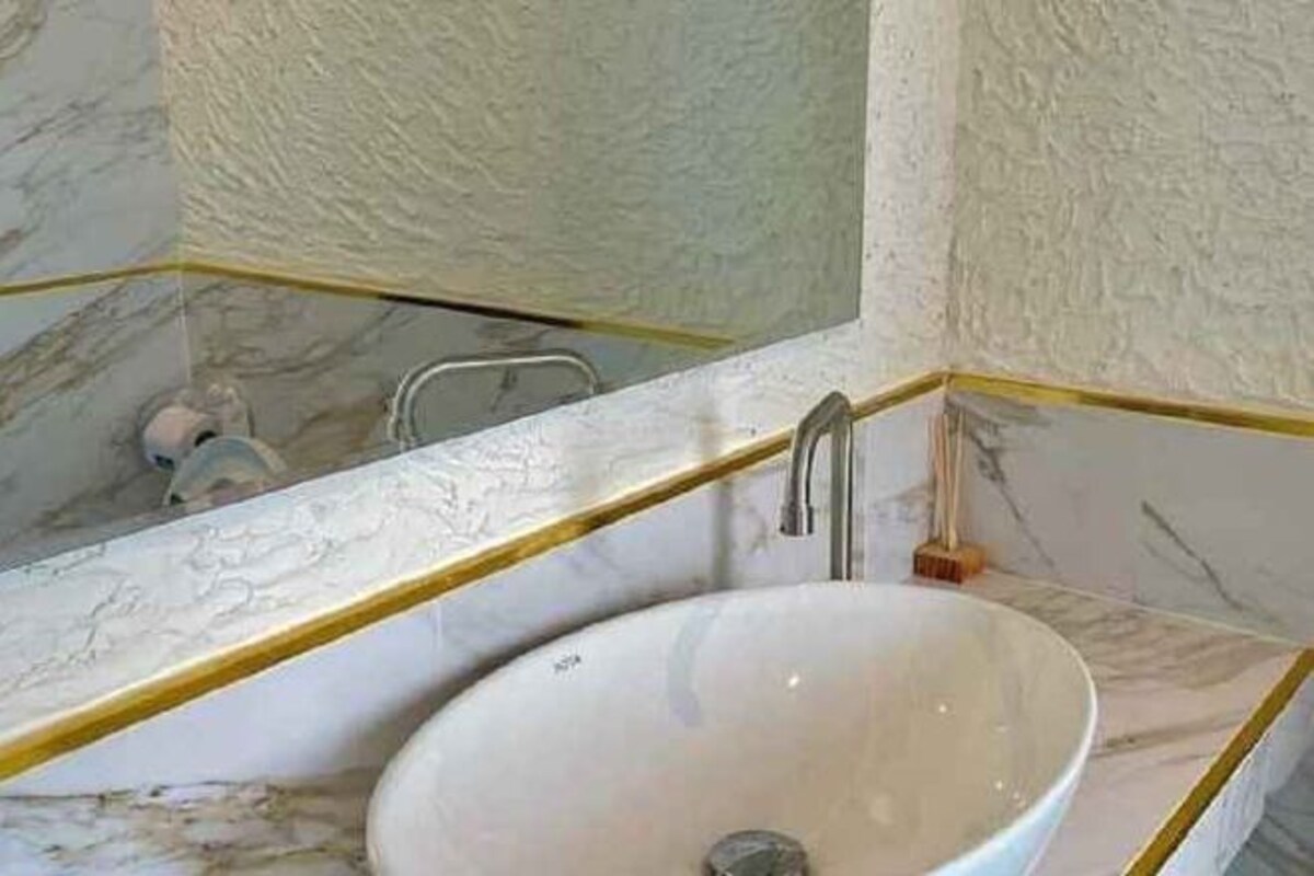 A bathroom with a white sink, a mirror, and marble walls.