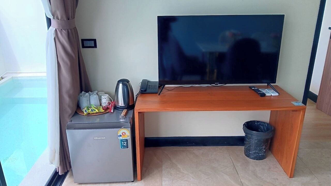 Huoneessa on taulutelevisio, pieni jääkaappi, kahvinkeitin ja roskakori.