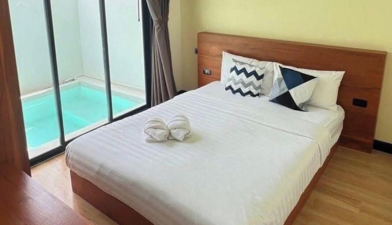 Een hotelkamer met een bed, een raam met uitzicht op een zwembad en een houten hoofdeinde.