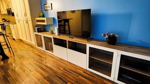 Ein modernes Wohnzimmer mit Holzboden, einem großen Flachbildfernseher und einer blauen Akzentwand.