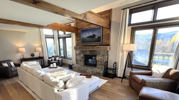 A spacious living room with a stone fireplace, large windows, and a modern sofa set.