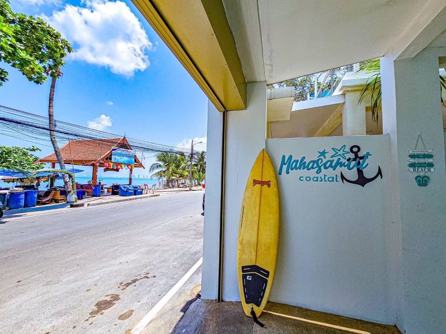A beachside shop with a surfboard and a sign reading "Mahasamut coastal".