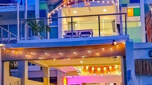 A two-story building with a balcony, string lights, and a surfboard. - Mahasamut coastal Poolvilla (Sattahip)