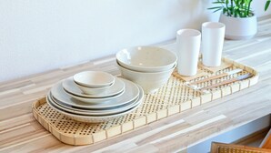 A neatly arranged dining set on a wooden tray with plates, bowls, and cups, accompanied by chopsticks, on a light-colored table. - Fukuoka Loft 303 (Fukuoka)