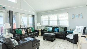 A spacious living room with leather sofas, a coffee table, and a TV stand.