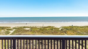 A beach view with a wooden deck in the foreground.
