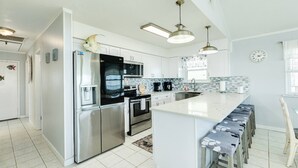 A modern kitchen with stainless steel appliances, a large island, and pendant lighting.